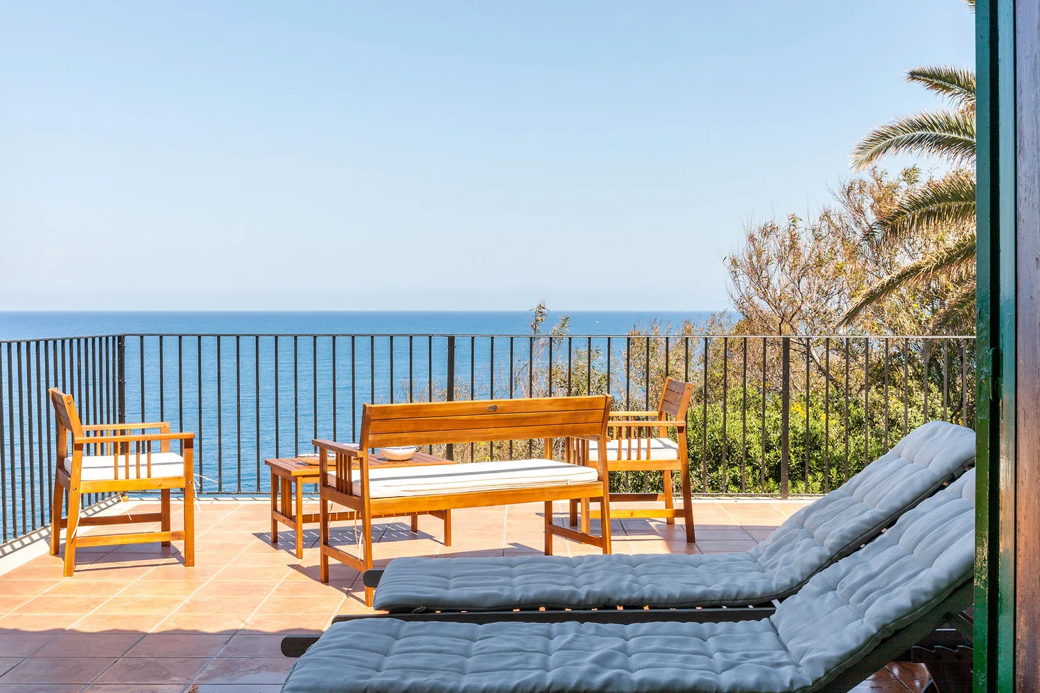 A seaside terrace with lounge seating and a railing overlooking the ocean.