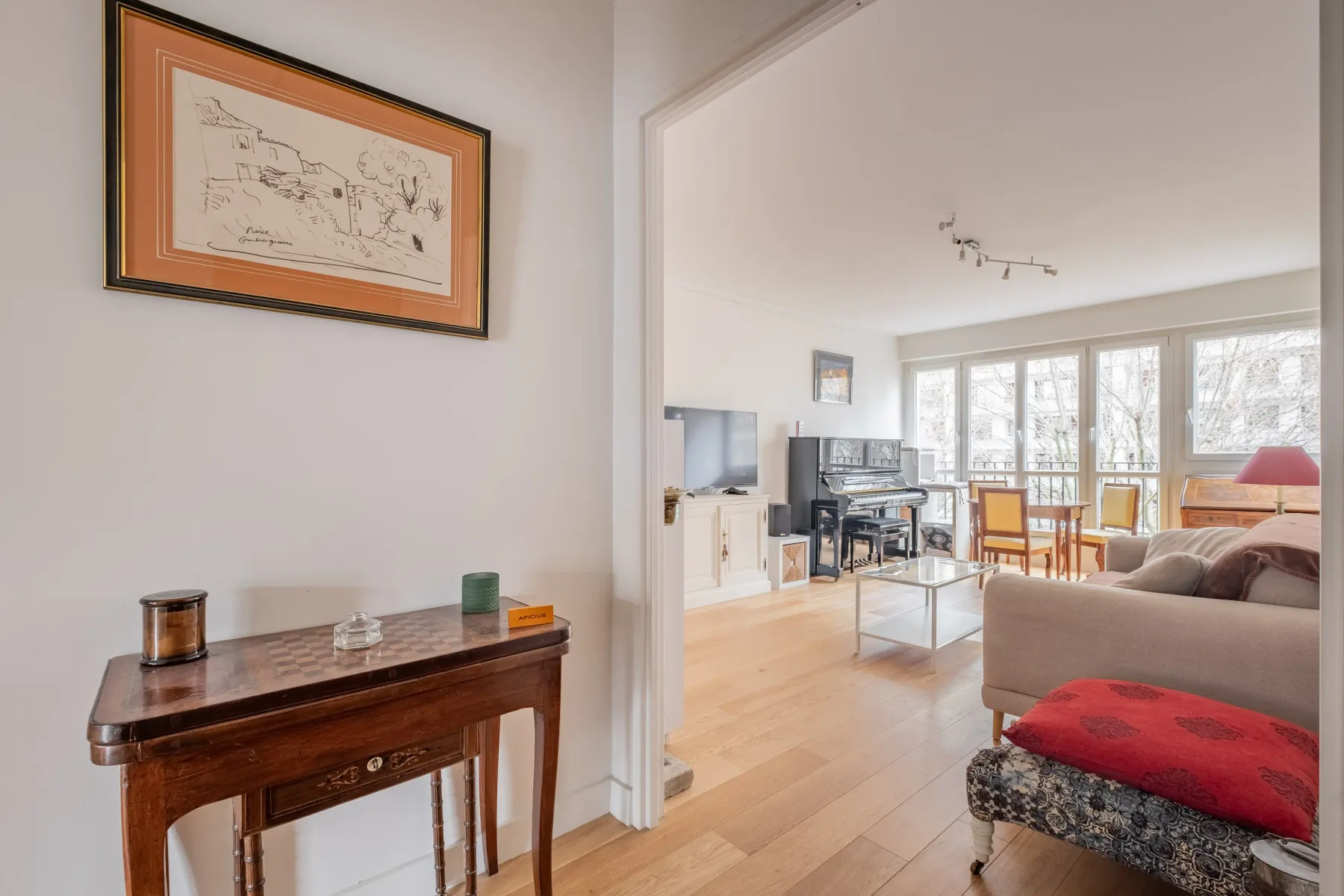 A bright living room with seating, a television, and large windows.