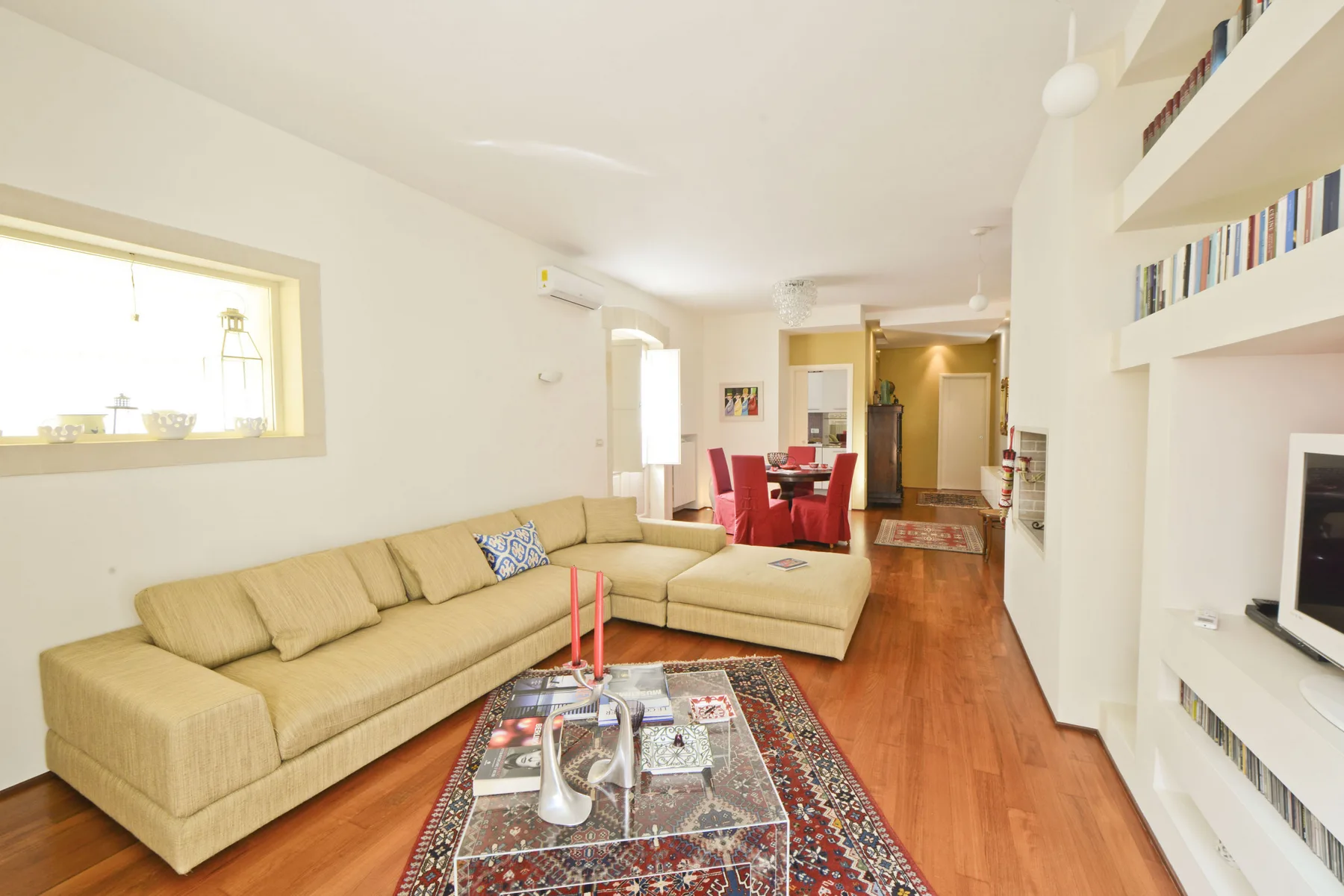 A bright living room with beige seating and a dining area beyond.