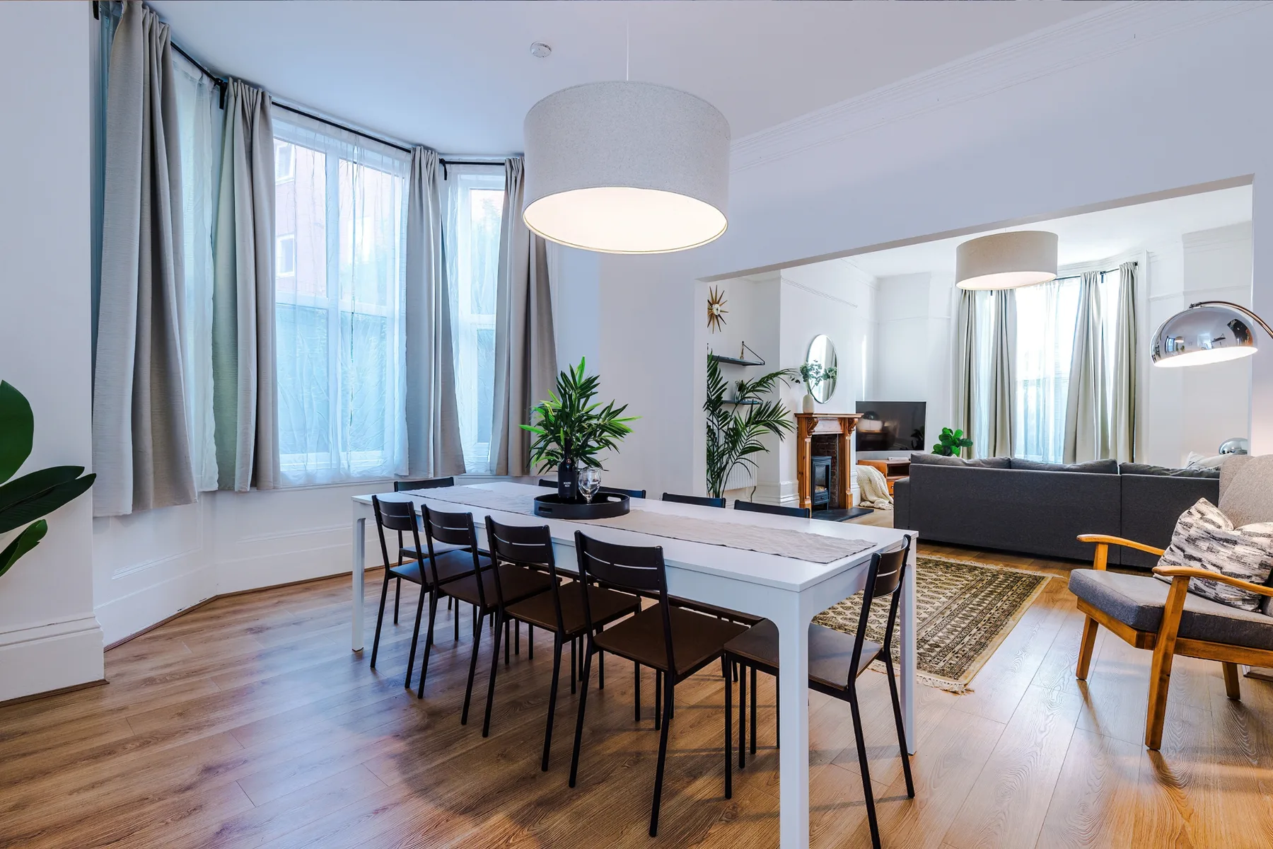 A bright open-plan living and dining area with a long table and large windows.