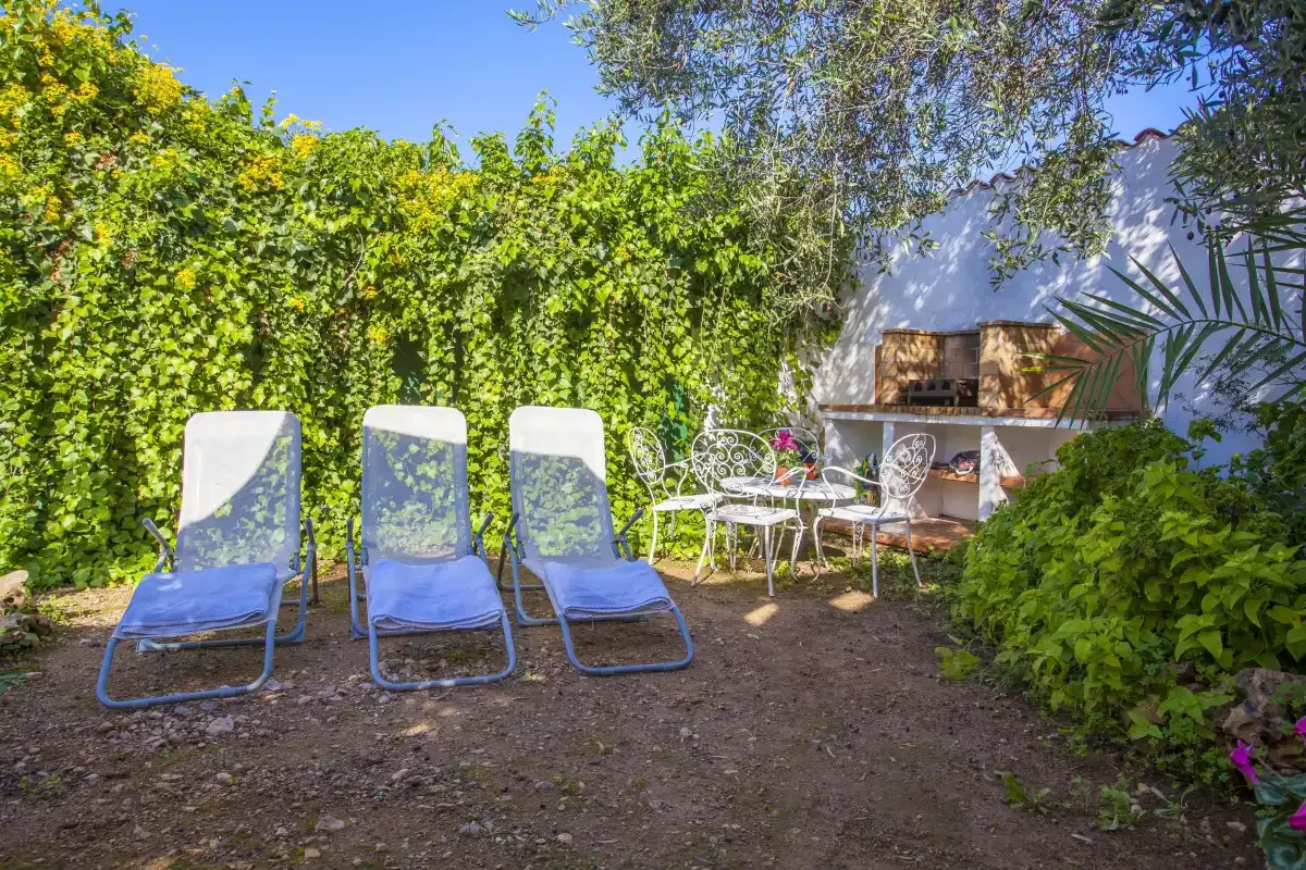 A garden seating area with lounge chairs, a table, and leafy surroundings.