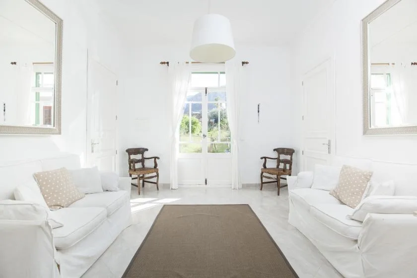 A bright living room with white seating and a large rug.