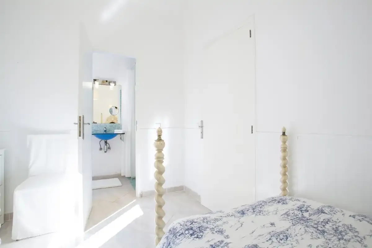 A bright bedroom with a bed and an open doorway to a bathroom.
