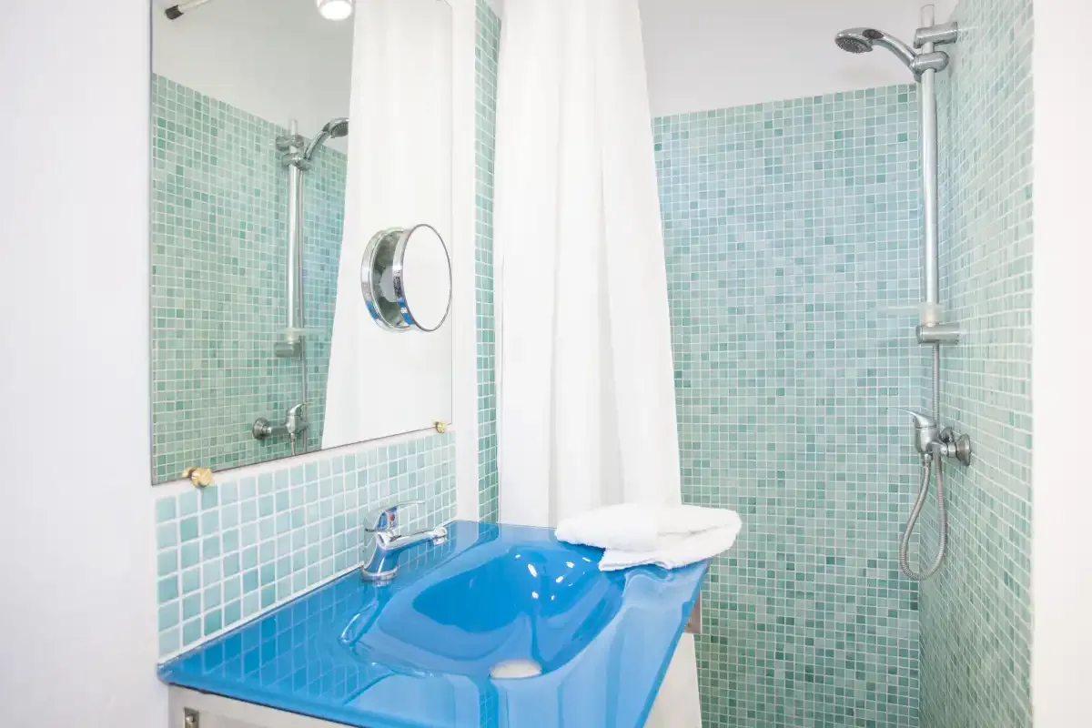 A tiled bathroom with a blue sink and shower.