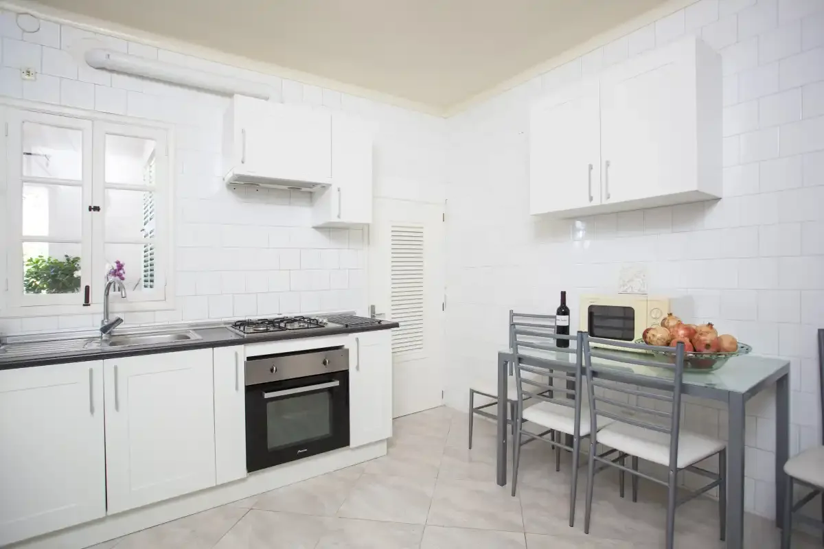 A bright kitchen with white cabinets, a stove, and a dining table.