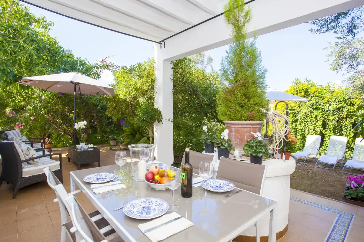 A covered outdoor dining area opens onto a garden with patio seating.