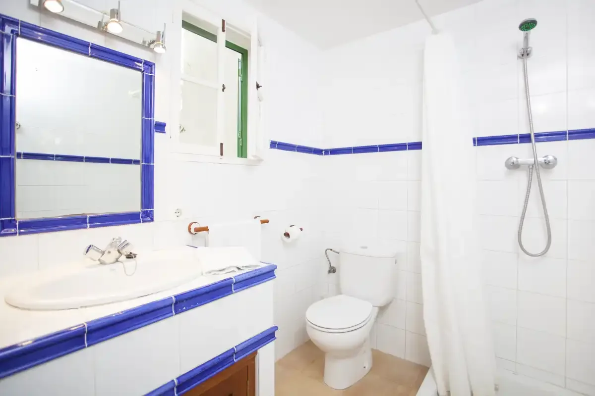 A bright bathroom with a sink, toilet, and shower.