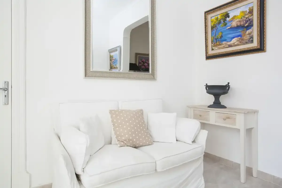 A bright living room with white seating and framed artwork.
