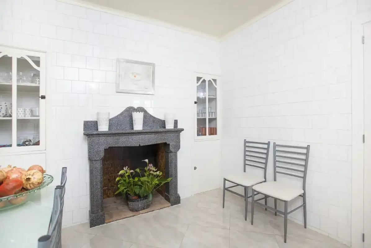 A bright tiled dining area with a fireplace and two chairs.