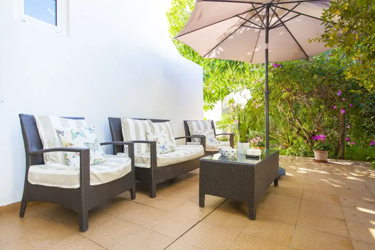 An outdoor patio has cushioned seating and a large shade umbrella.