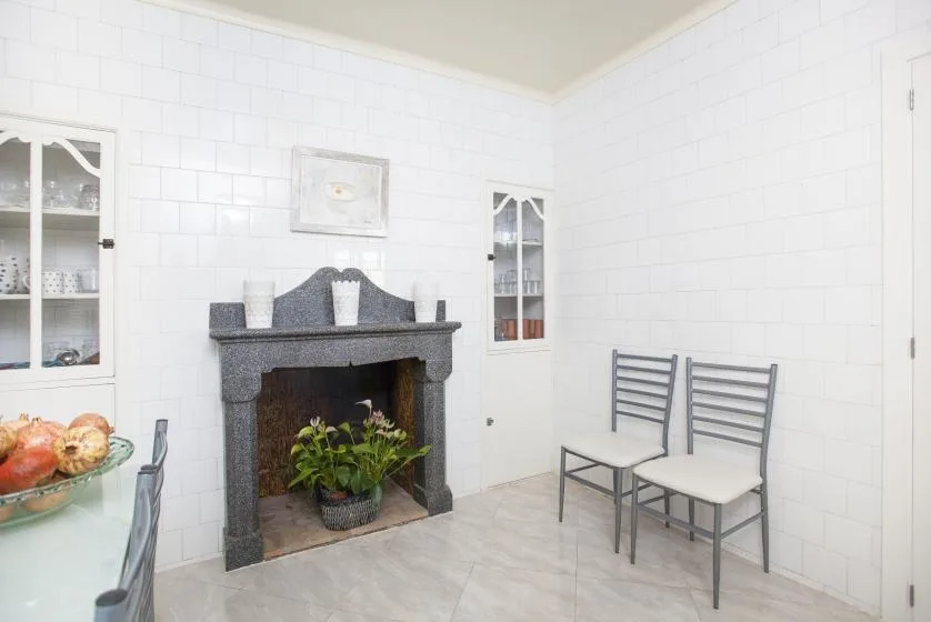 A bright tiled dining area with a fireplace and two chairs.
