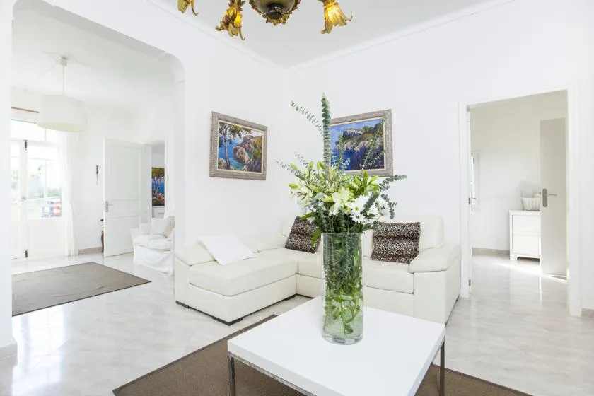 A bright living room with white seating and a flower arrangement on the coffee table.