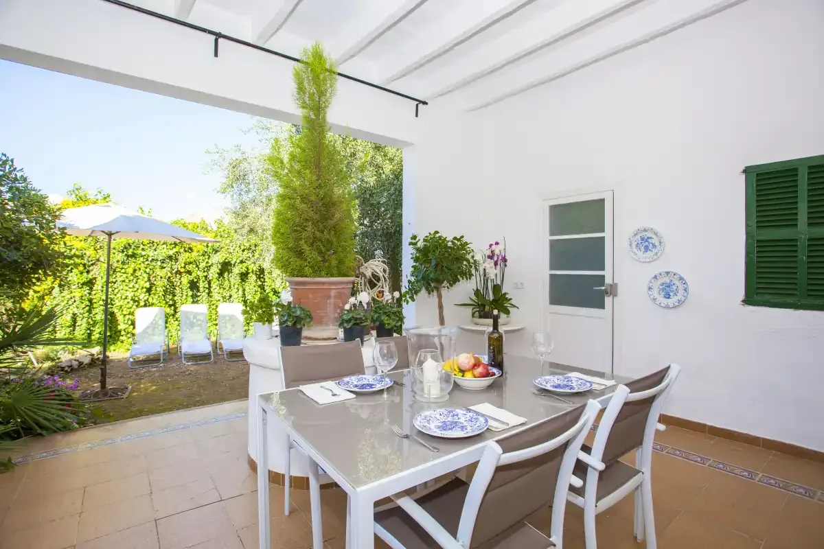 A covered dining area opens onto a garden with outdoor seating.