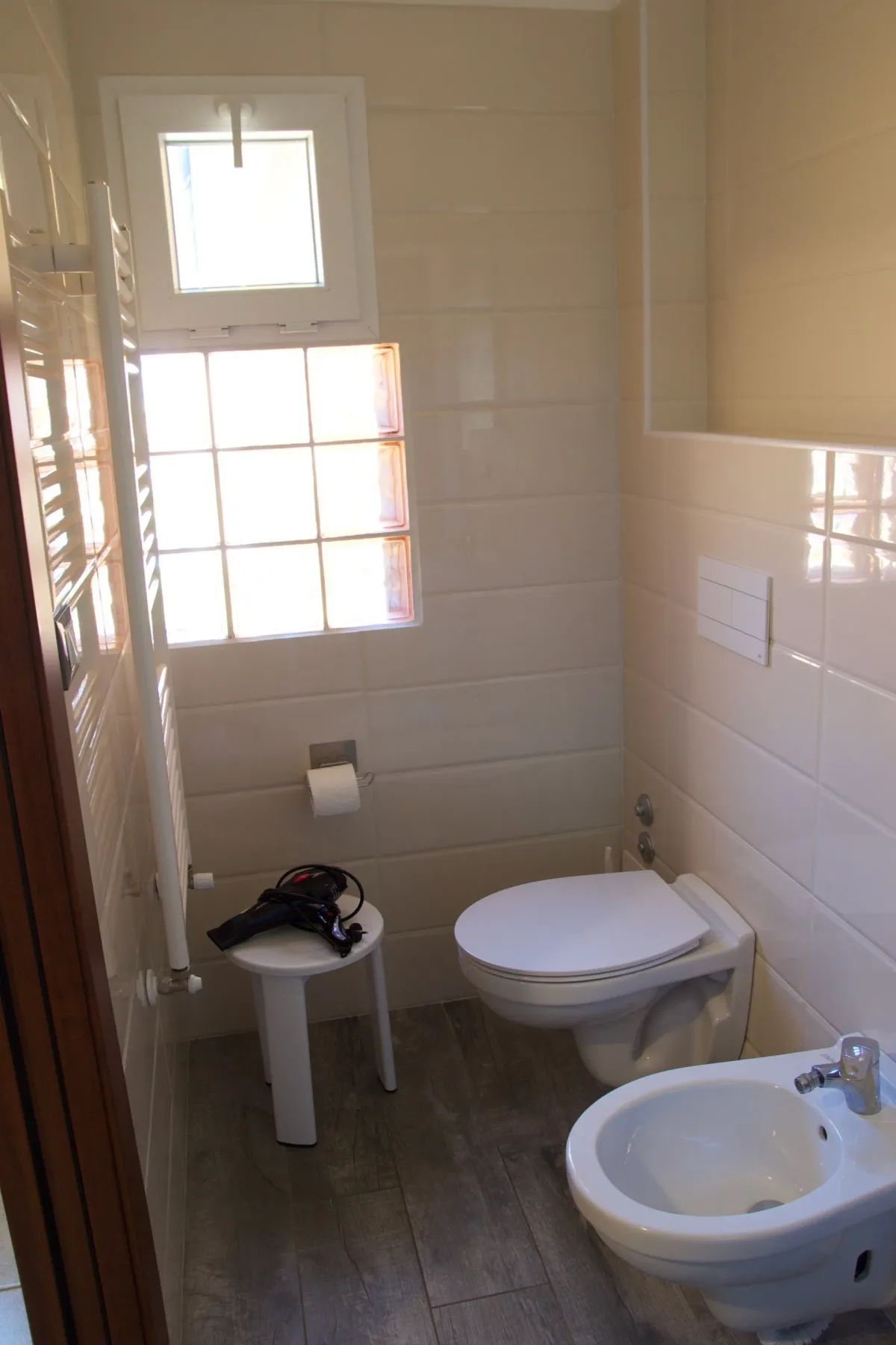 Baño con dos inodoros, un bidé y una ventana.