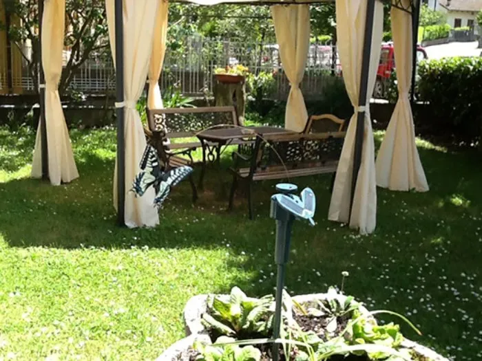 Jardín con cenador, mesa y sillas.