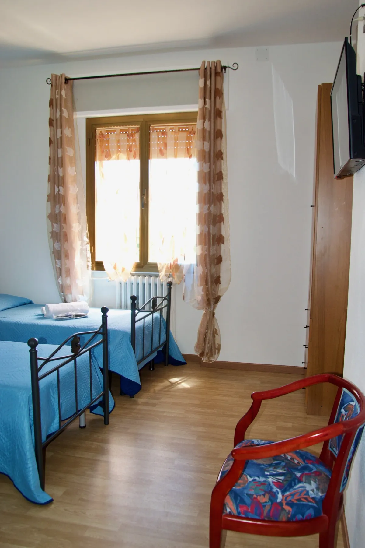 Habitación de huéspedes con dos camas y una silla roja.