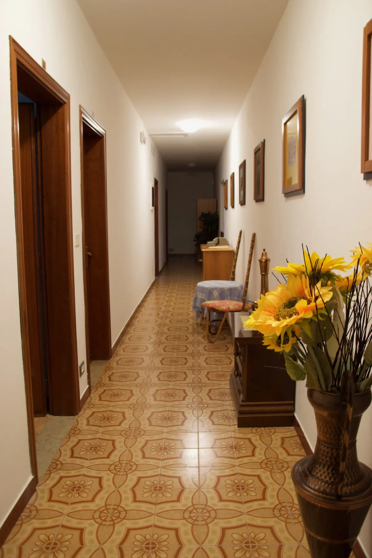 Pasillo largo con un jarrón de flores.