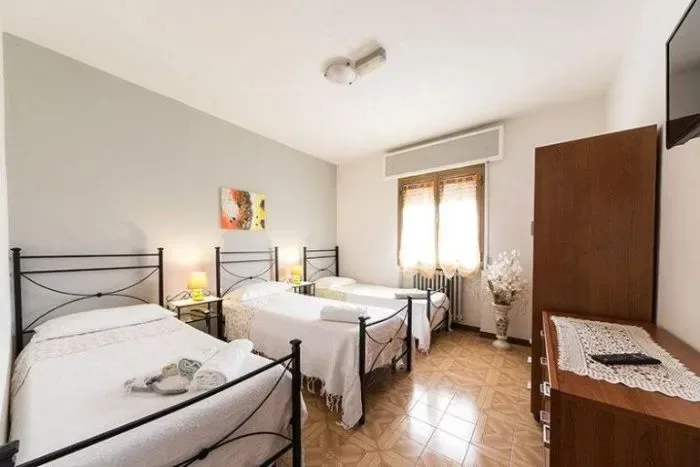Habitación de huéspedes con tres camas y un televisor de pantalla plana.