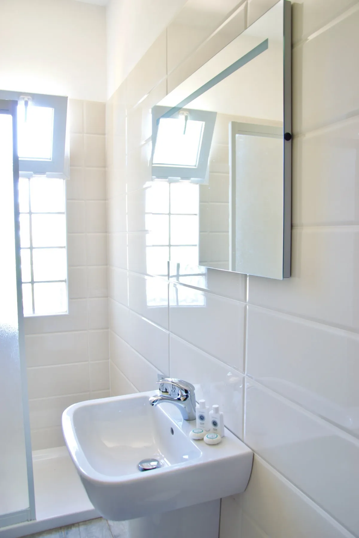Baño con lavabo, espejo y ducha.