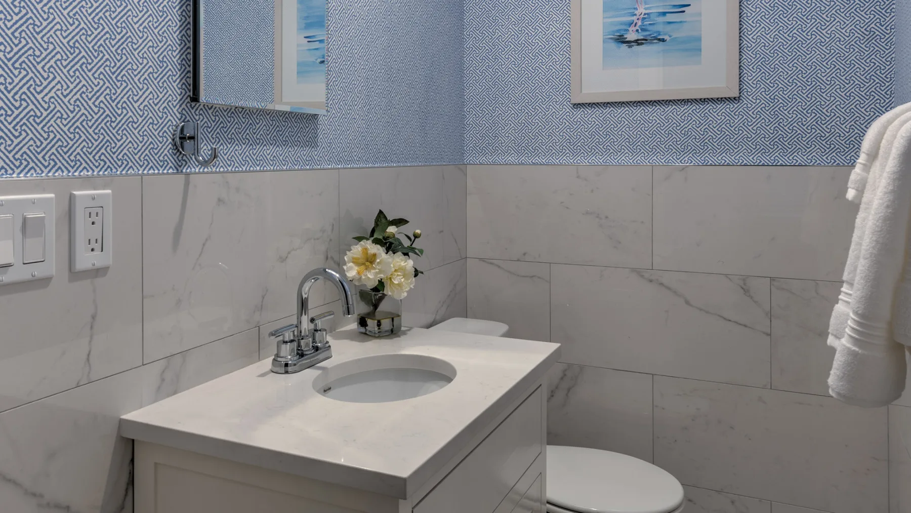 Un tocador de baño con lavabo, flores e inodoro.