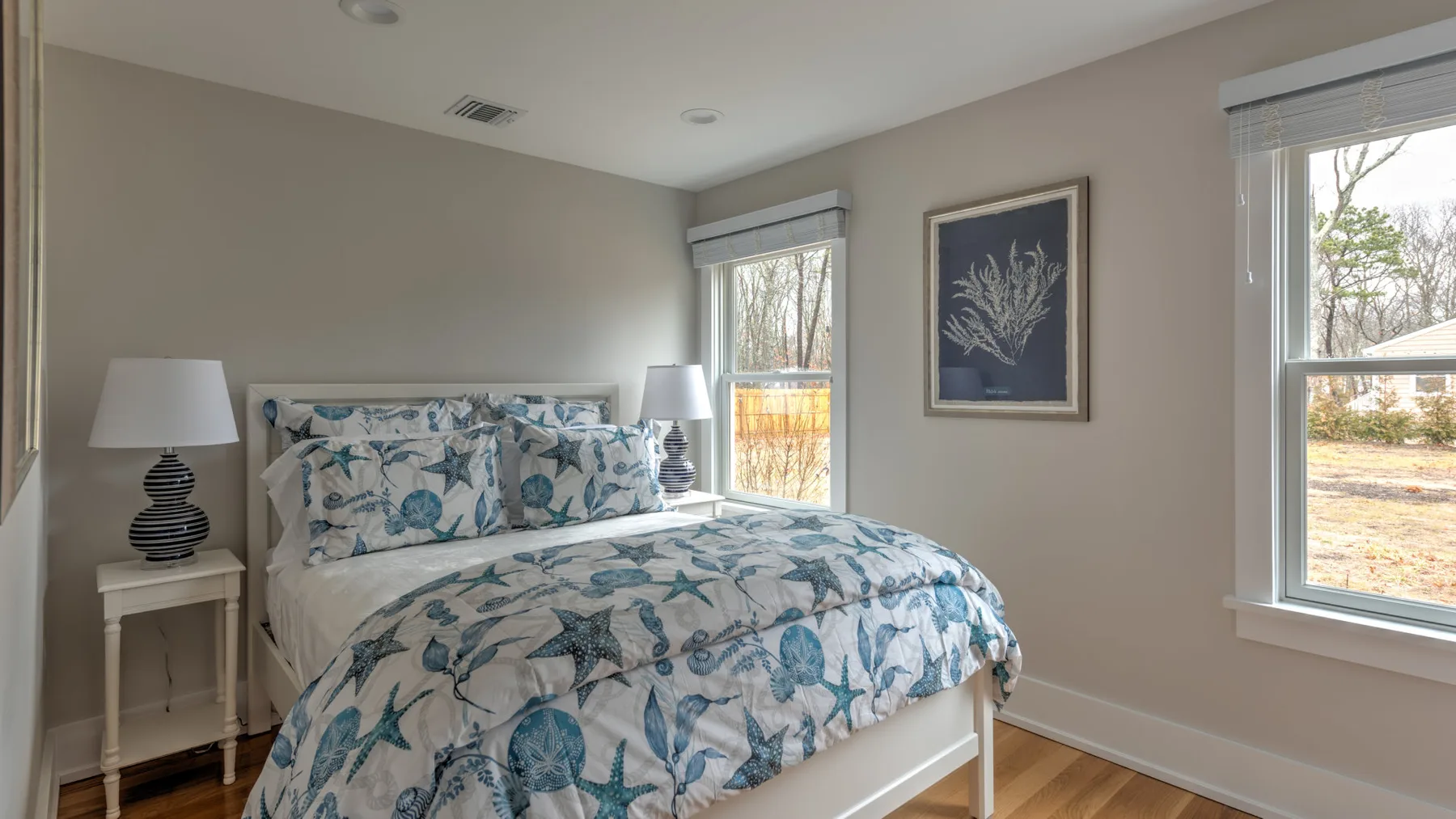 Un dormitorio con una cama cubierta de ropa de cama estampada azul y ventanas.