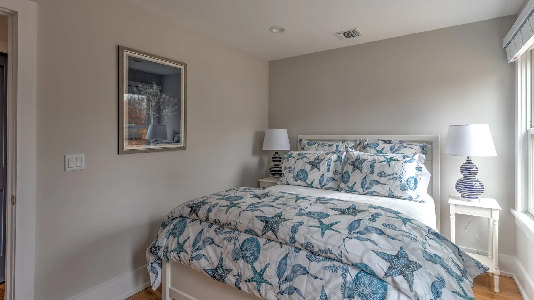 Un dormitorio con una cama vestida con ropa de cama estampada en azul y blanco.