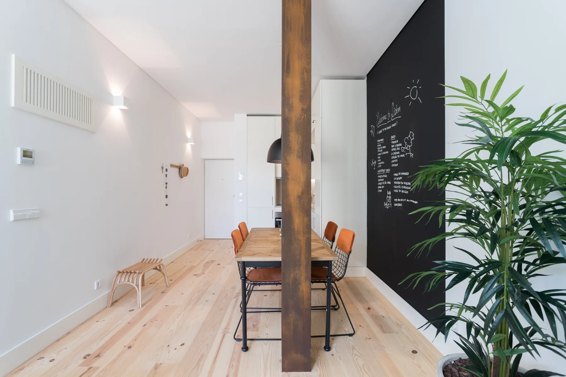 A dining area with a wooden table, orange chairs, and a black chalkboard wall.