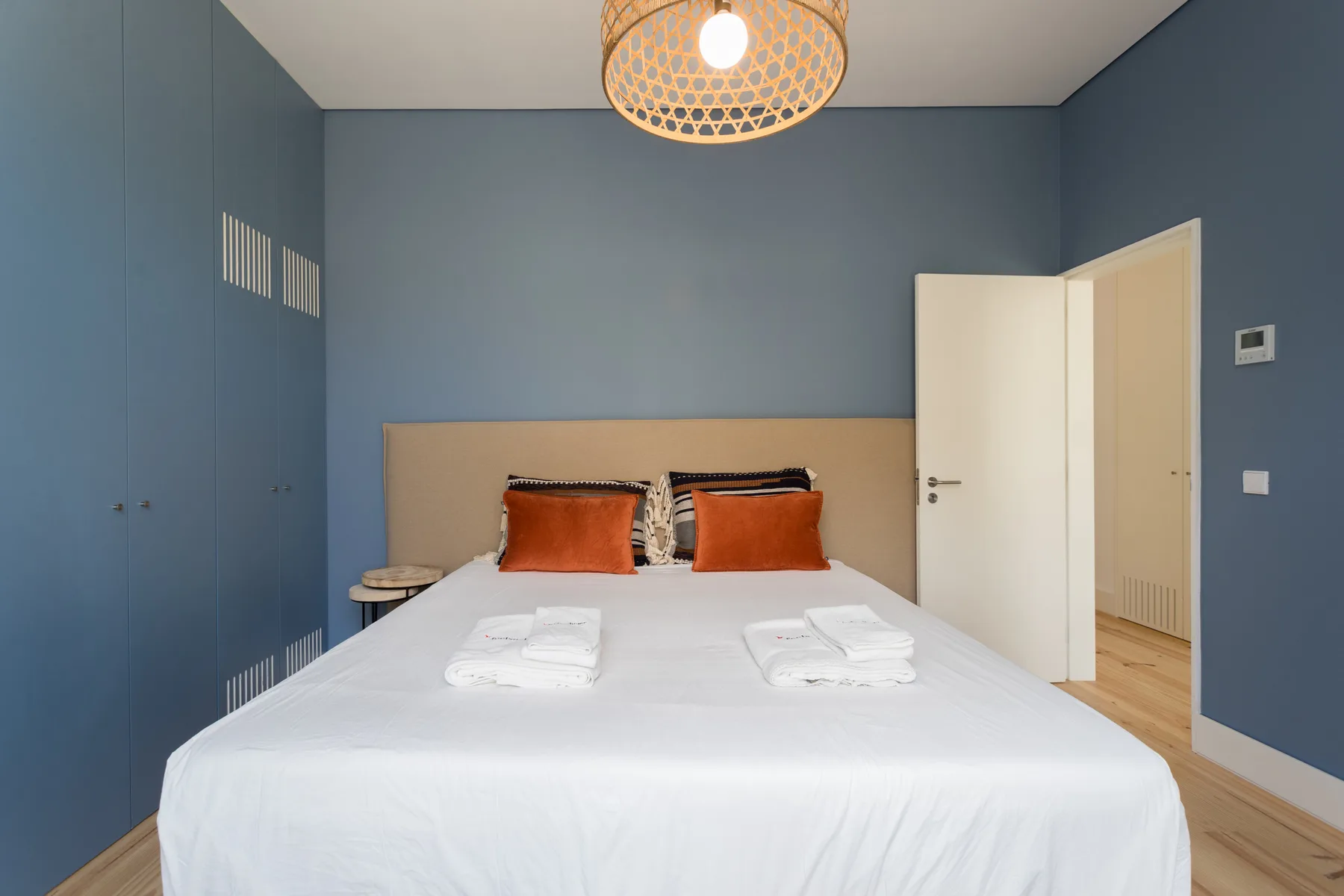 A bedroom with a neatly made bed and blue walls.