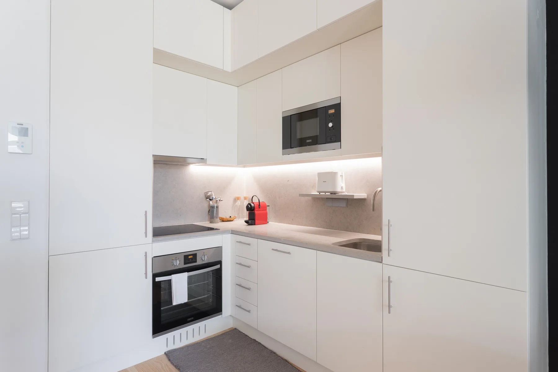 A modern kitchen with white cabinets, built-in appliances, and a countertop.