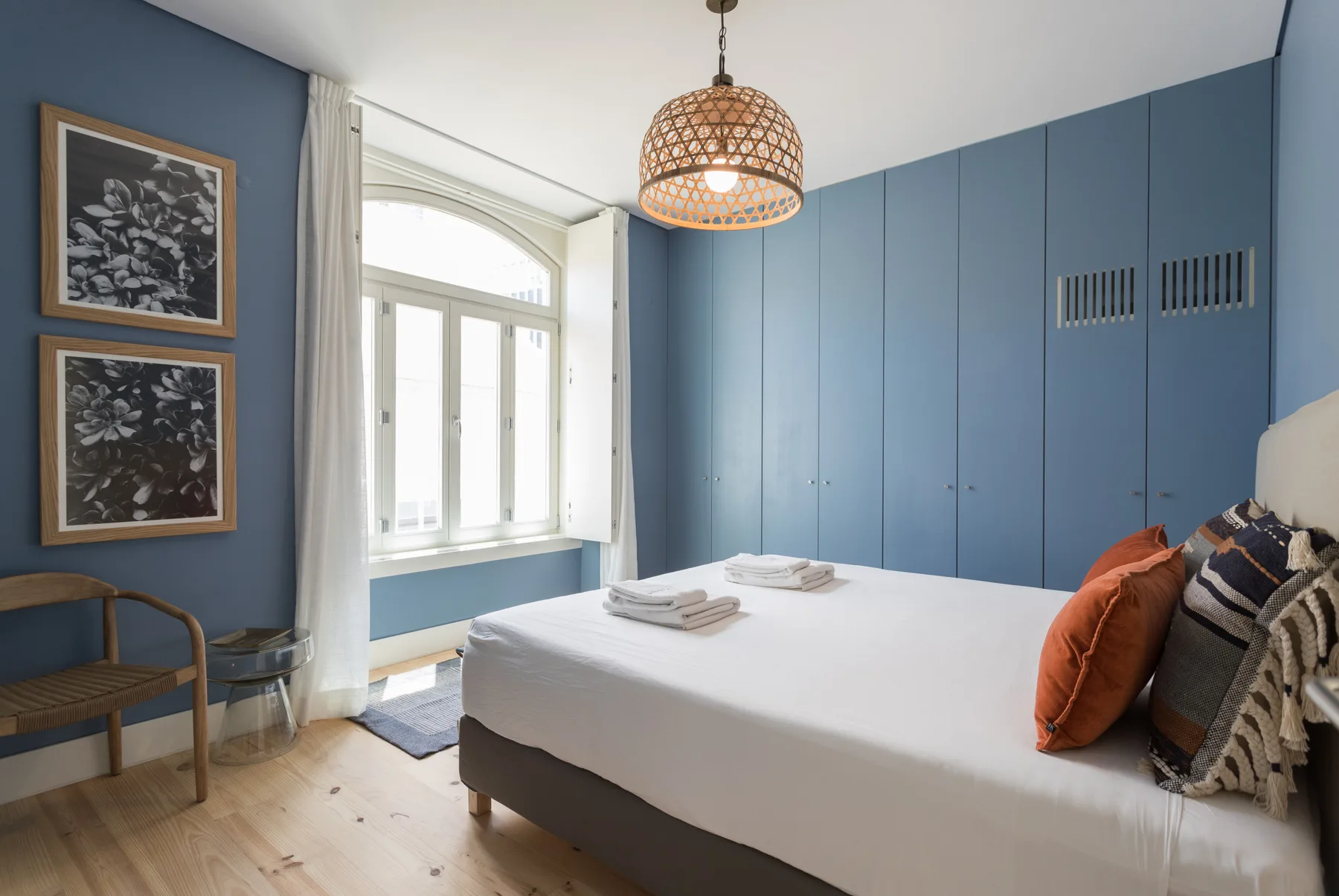 A bedroom with a neatly made bed and a large window.