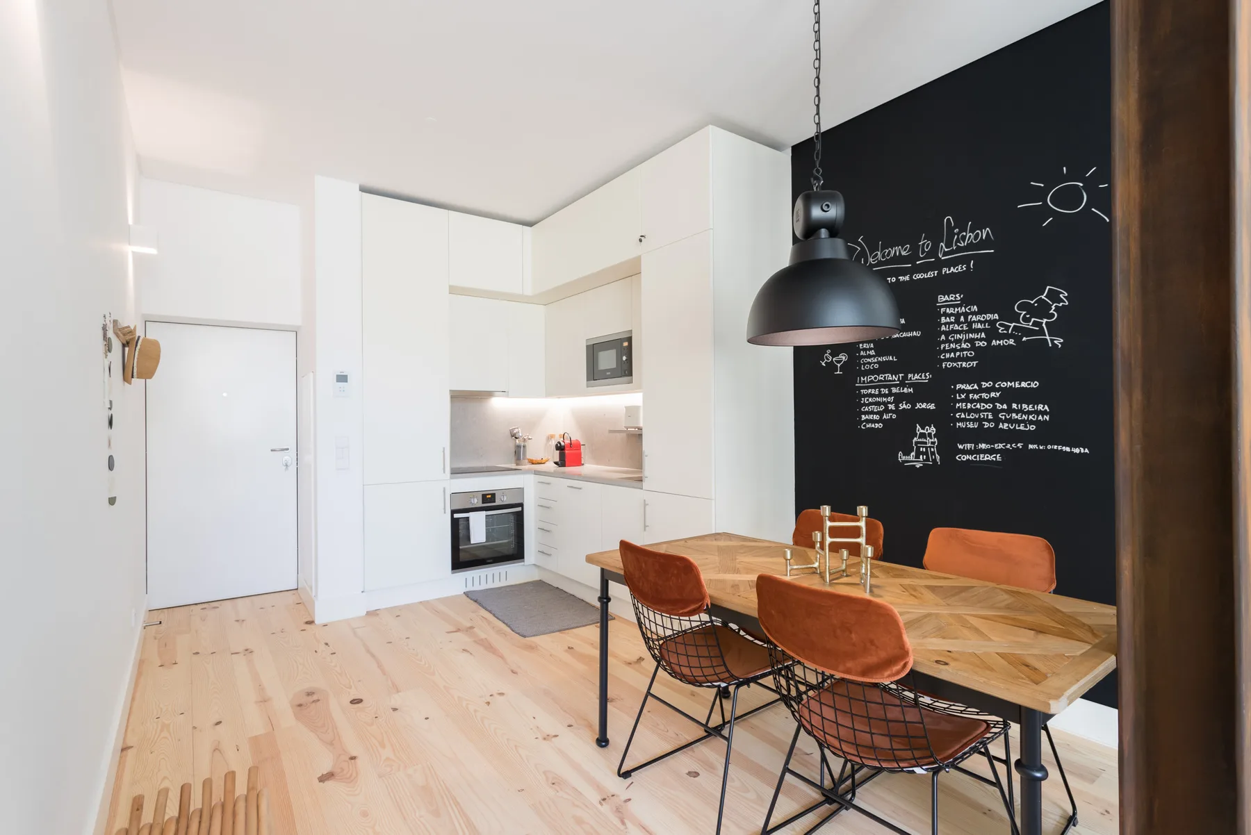 An open-plan kitchen and dining area with a wooden table beside a chalkboard wall.