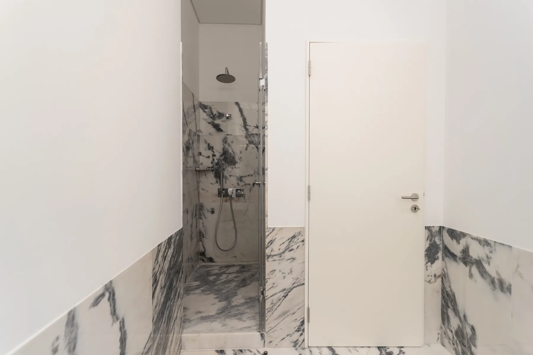 A bathroom with a walk-in shower and a white door.
