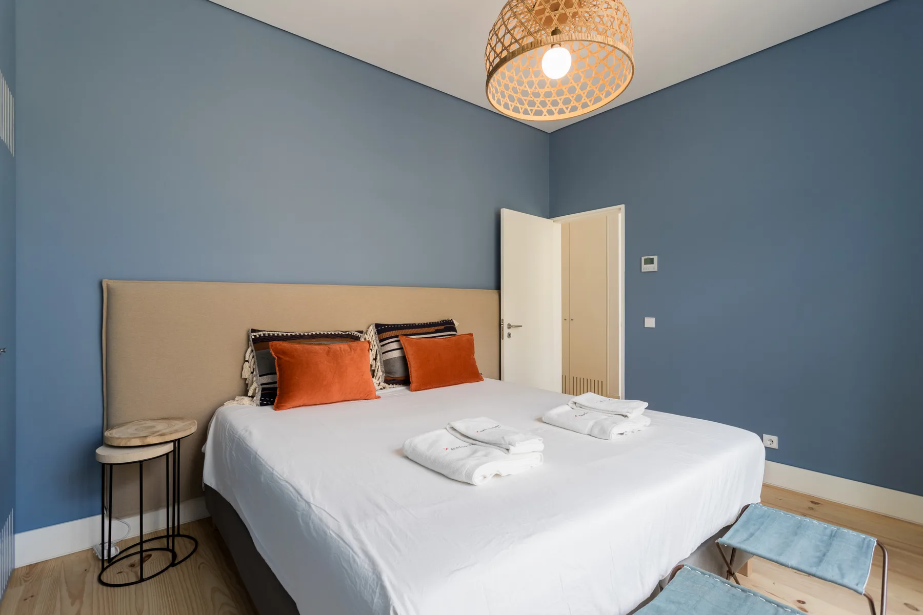 Un dormitorio con una cama bien hecha y paredes azules.
