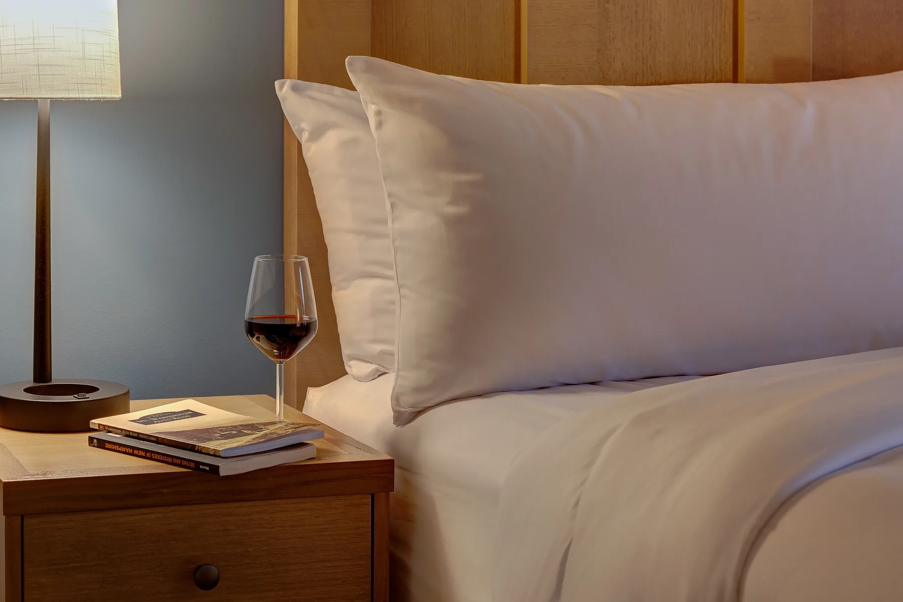 Vino y libros sobre una mesa de noche en una habitación
