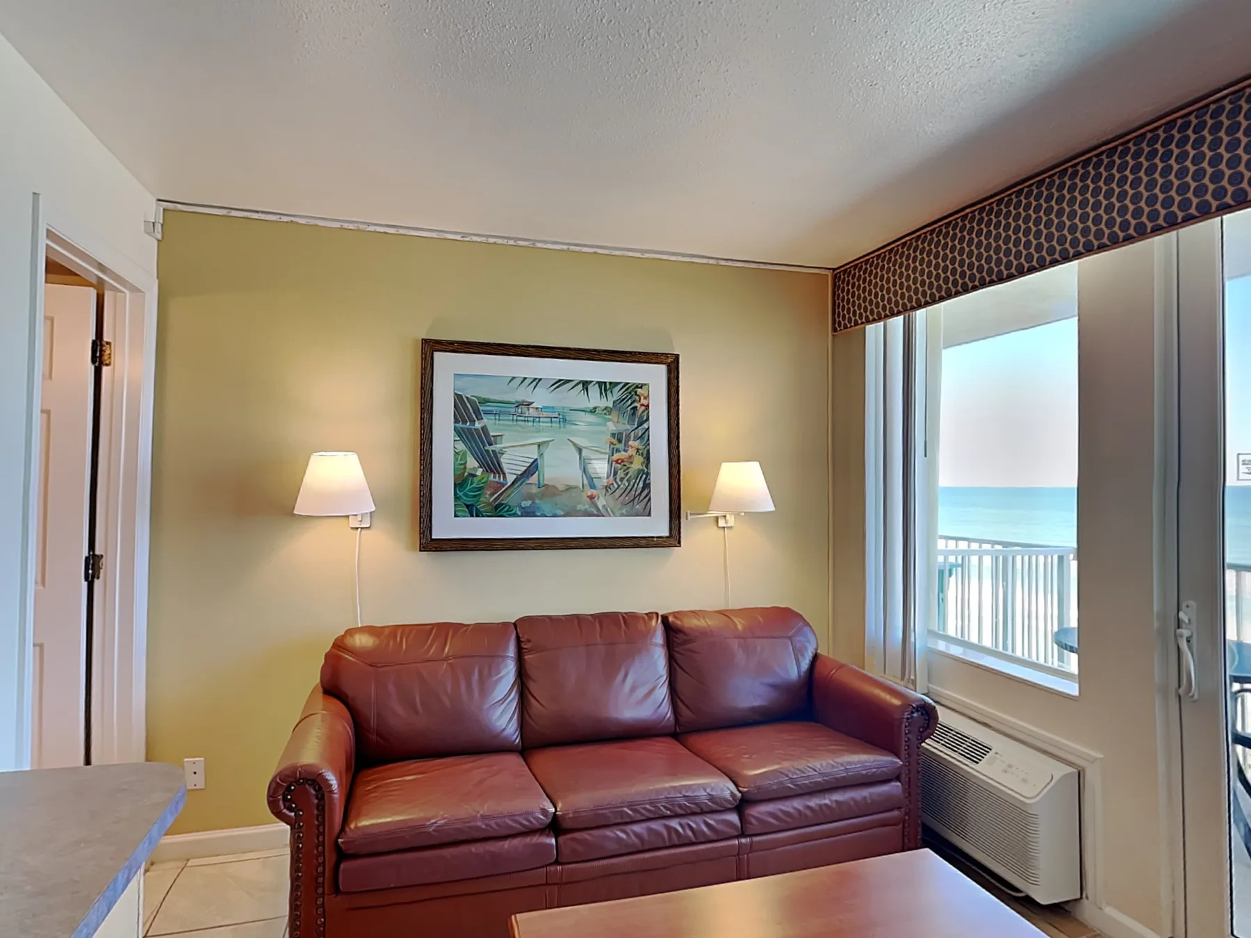 A living area with leather seating beside a bright window overlooking the water.