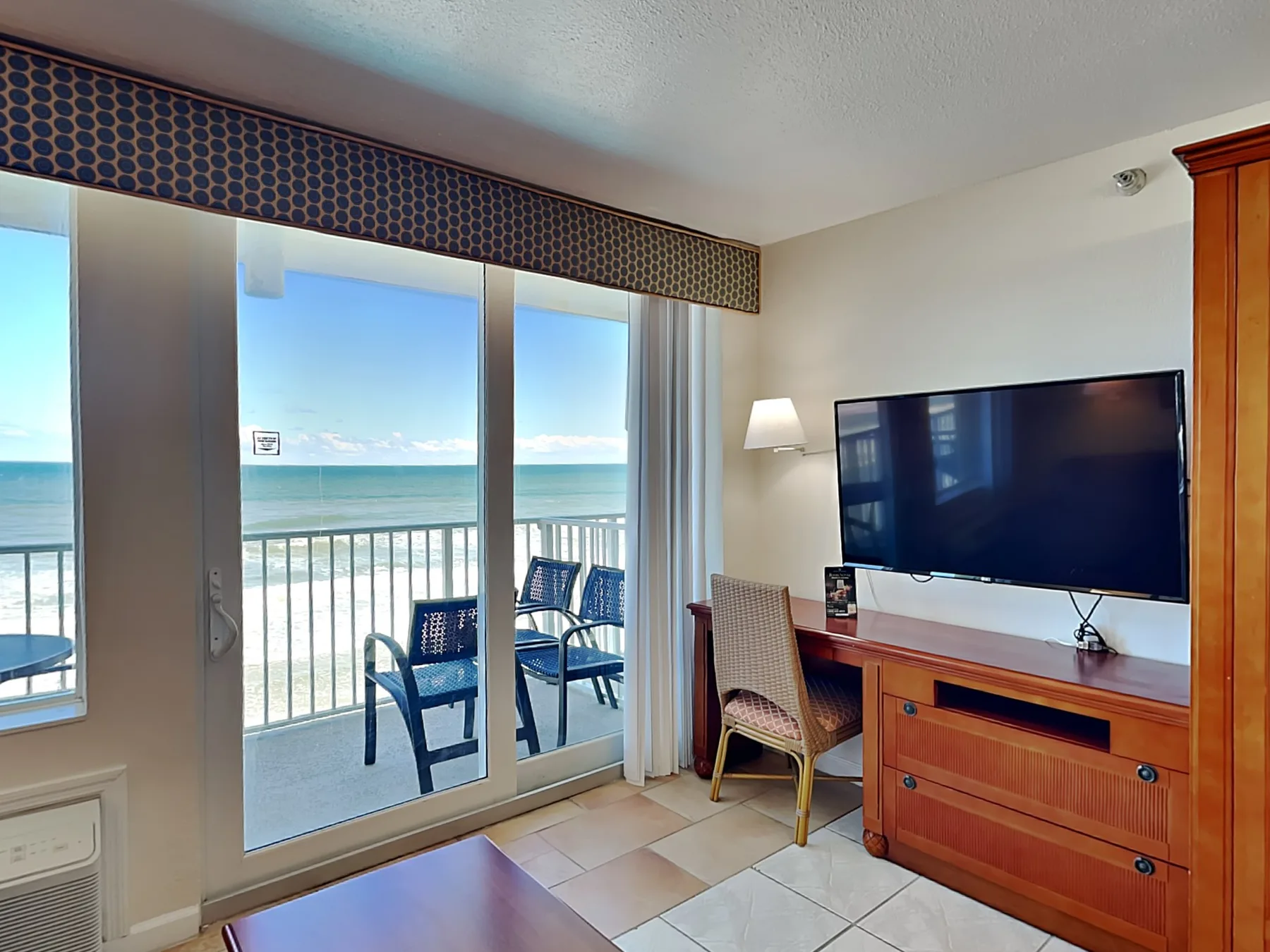 A bright living area opens onto a balcony overlooking the ocean.