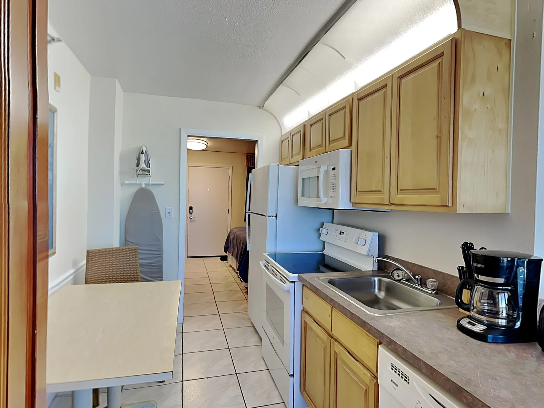 Una cocina compacta con gabinetes de madera, un refrigerador y una encimera.