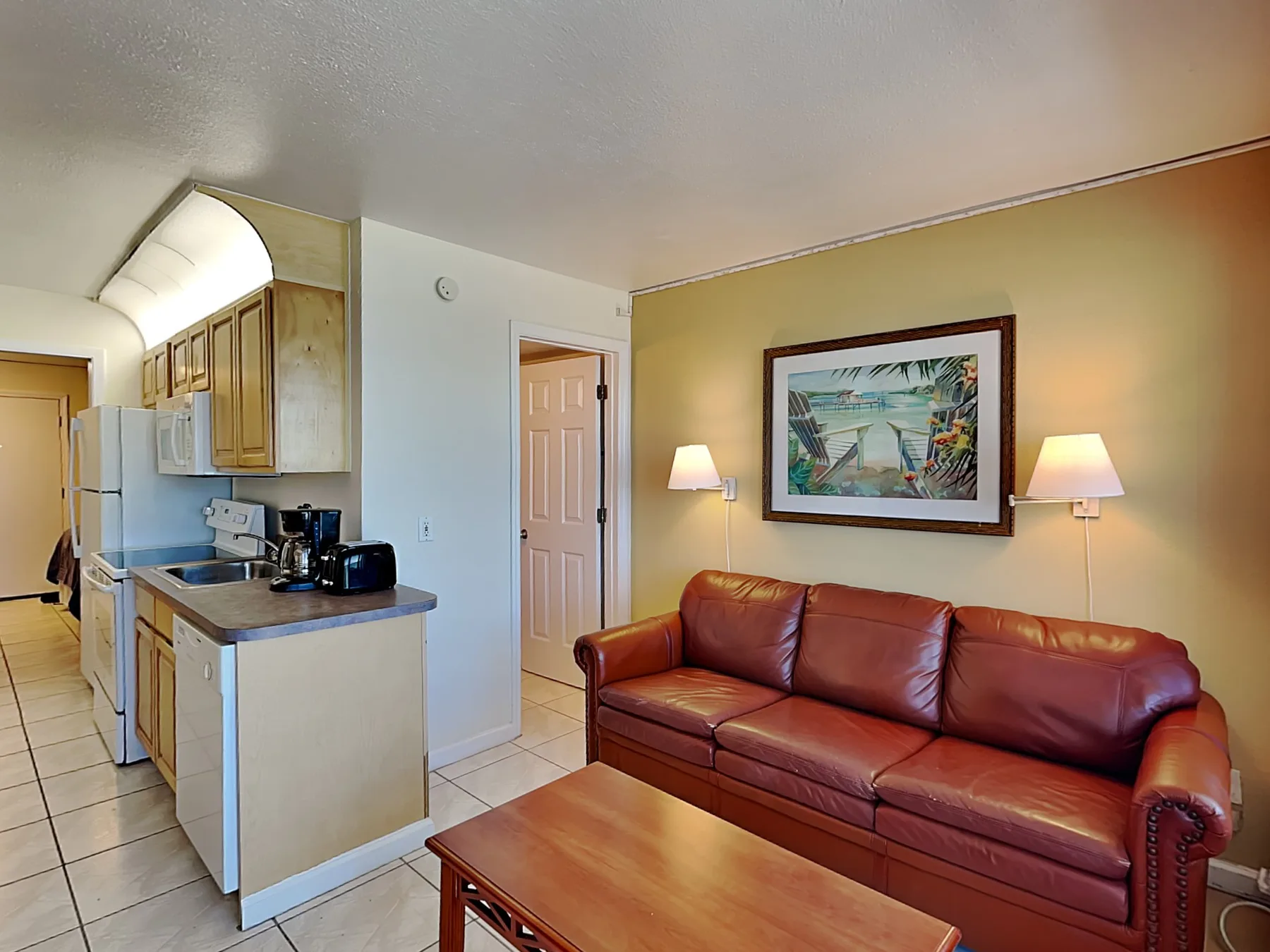A living area with a red leather sofa beside an open kitchen.