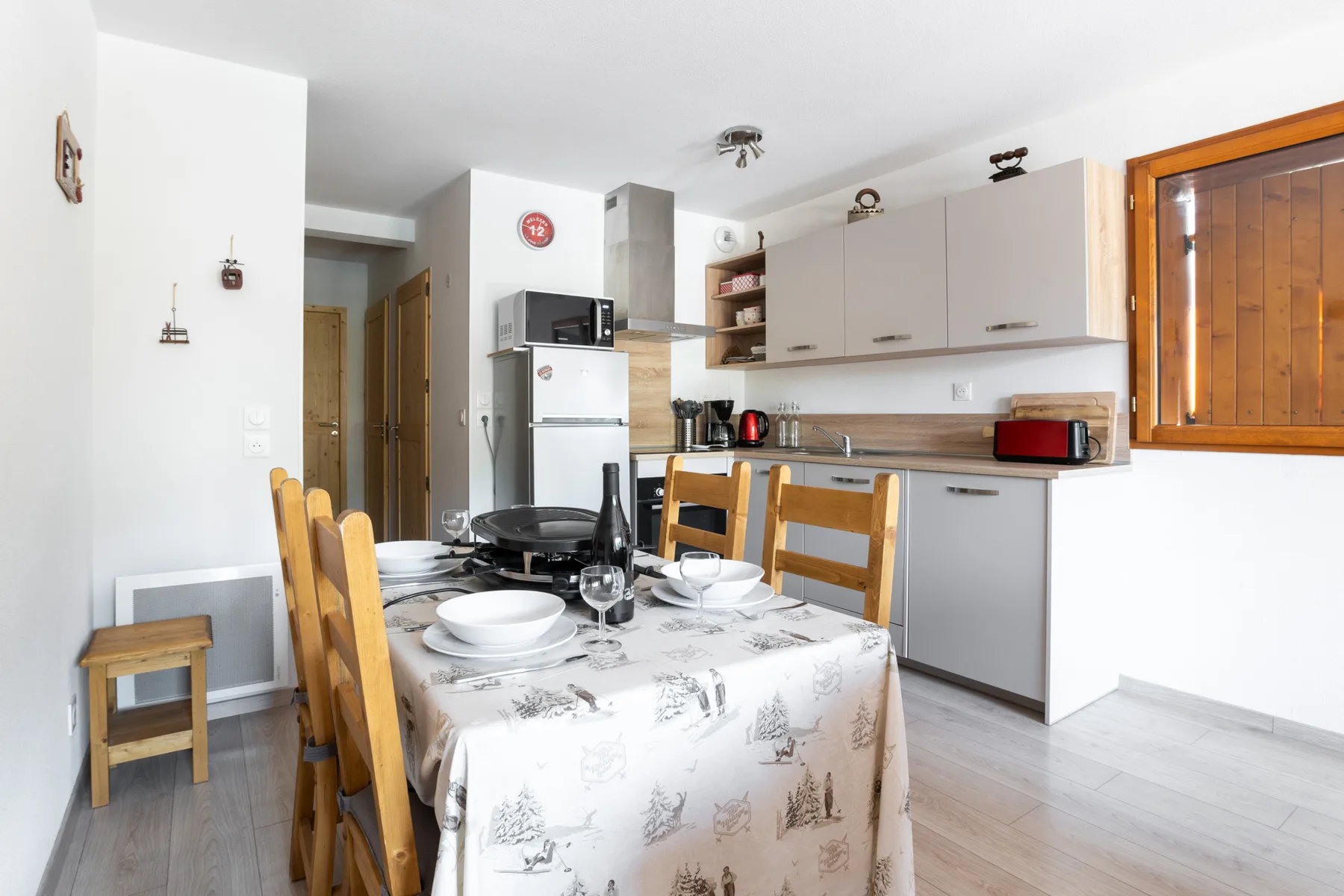 A dining area beside a compact kitchen, with a table set for a meal.