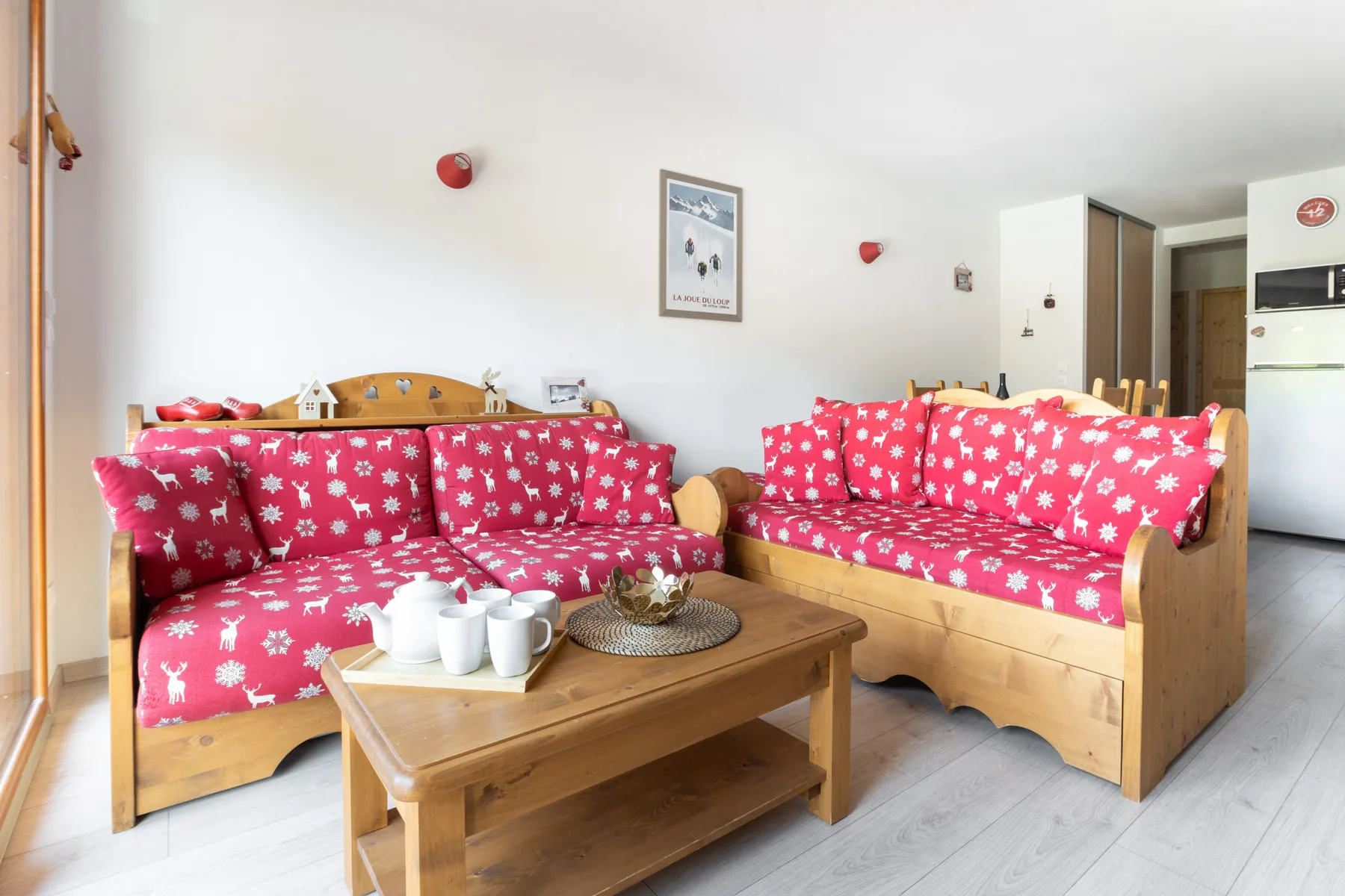 A living room with wooden seating covered in red floral fabric around a coffee table.