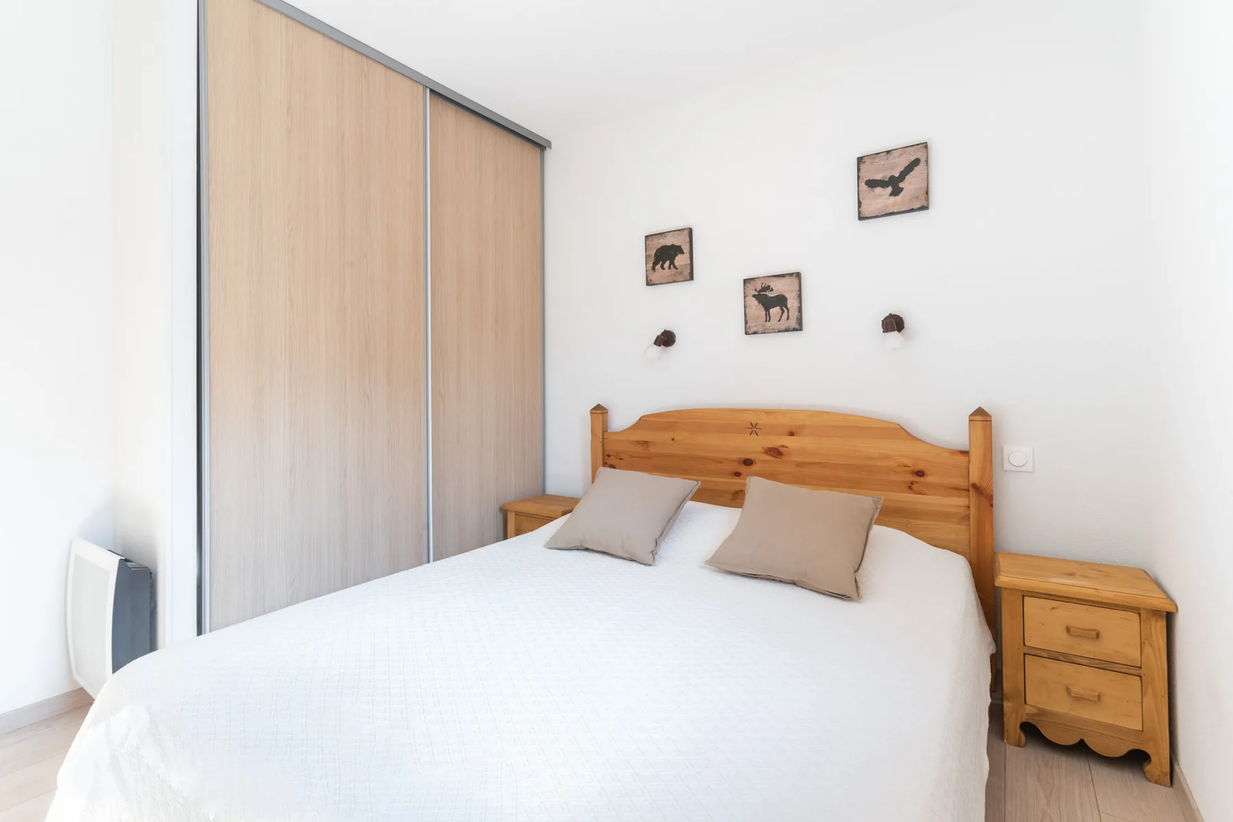 A bright bedroom with a bed and bedside table beside a wardrobe.