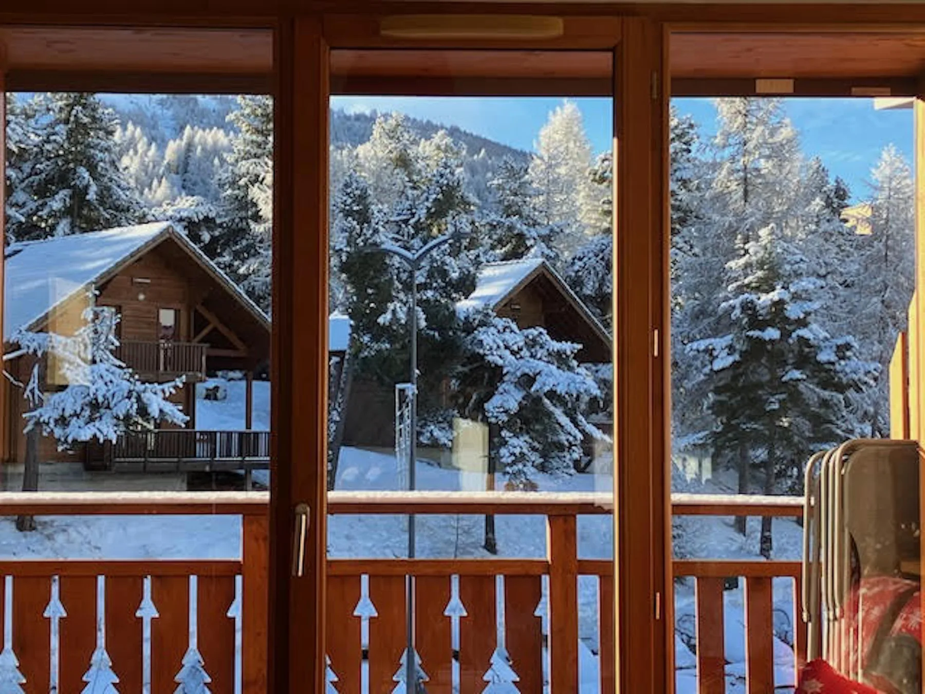 Snow-covered trees and wooden cabins are visible through a large window.