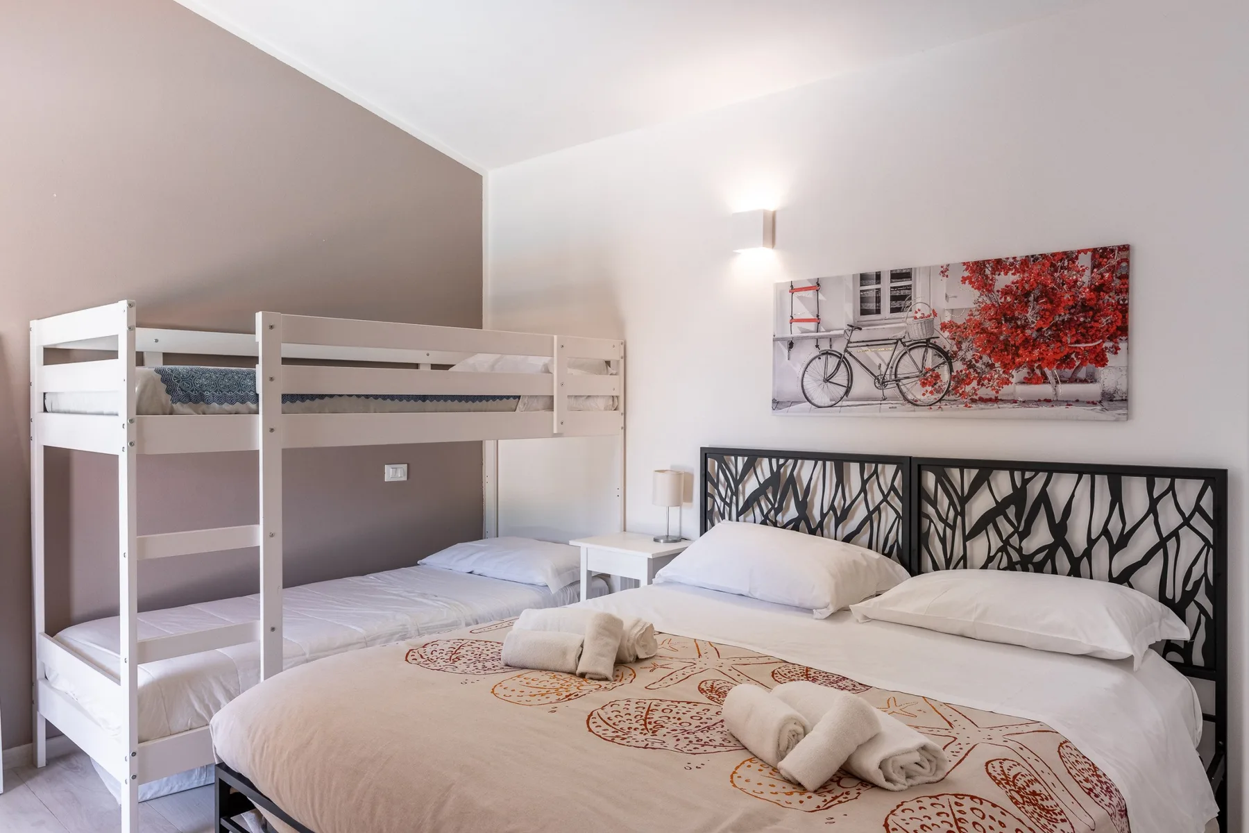 Un dormitorio con una litera blanca sobre una cama más grande.