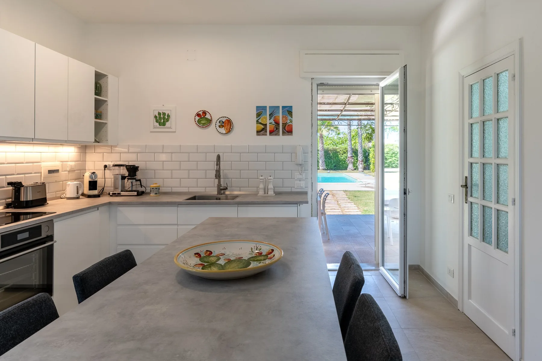 Una cocina luminosa con una mesa grande y una puerta abierta al exterior.