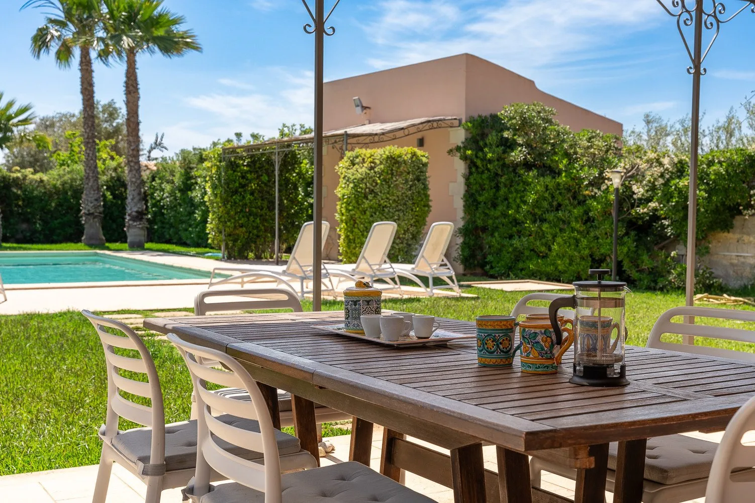 Una zona de comedor al aire libre con una mesa de madera junto a una piscina.