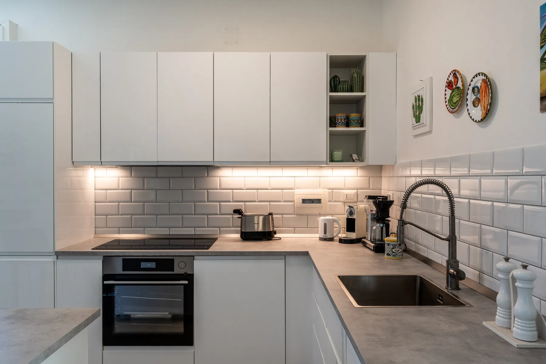 Una cocina moderna con gabinetes blancos, una placa de cocina y un fregadero.