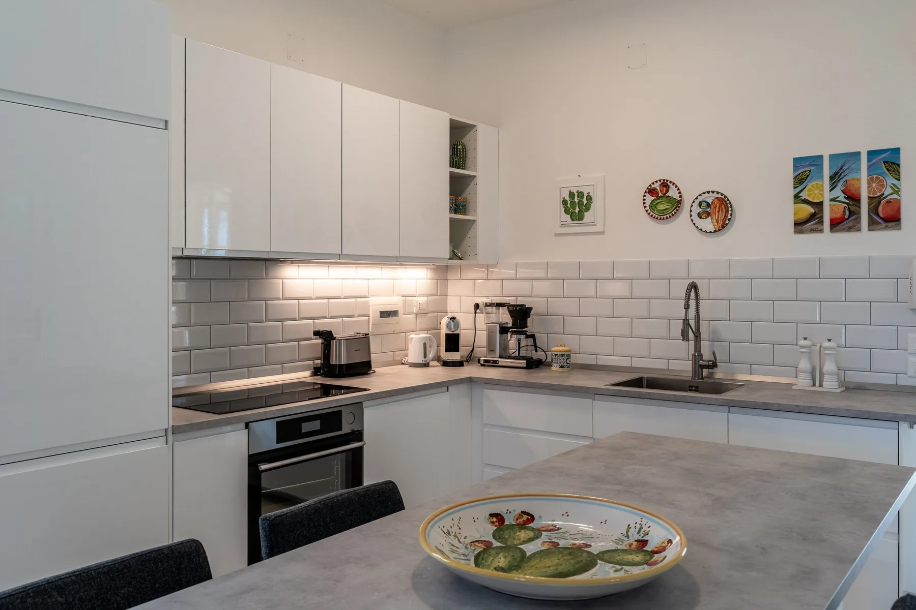 Una cocina moderna con gabinetes blancos, azulejos en la pared y una zona para comer.