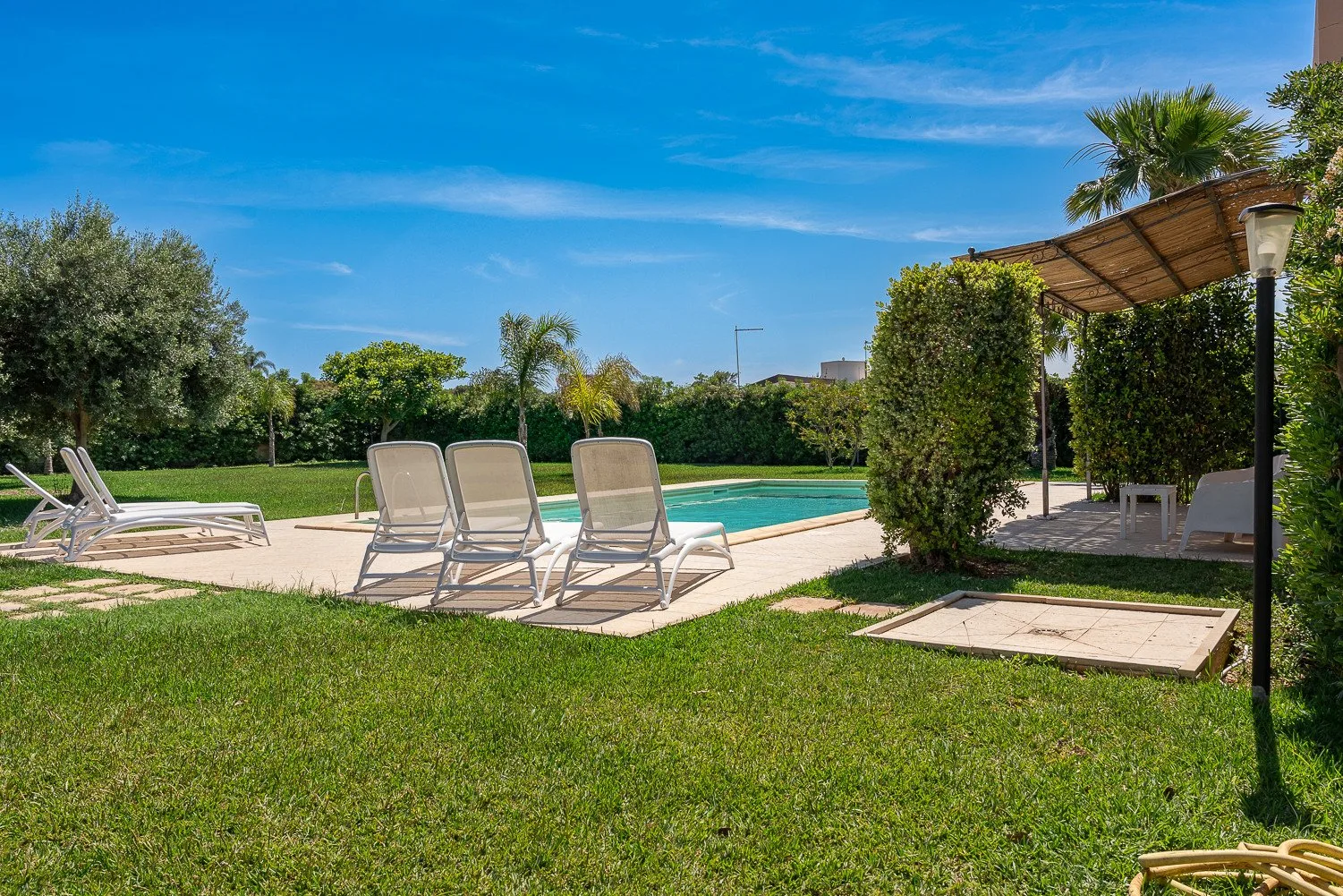 Una zona de piscina al aire libre con asientos junto a un césped verde.