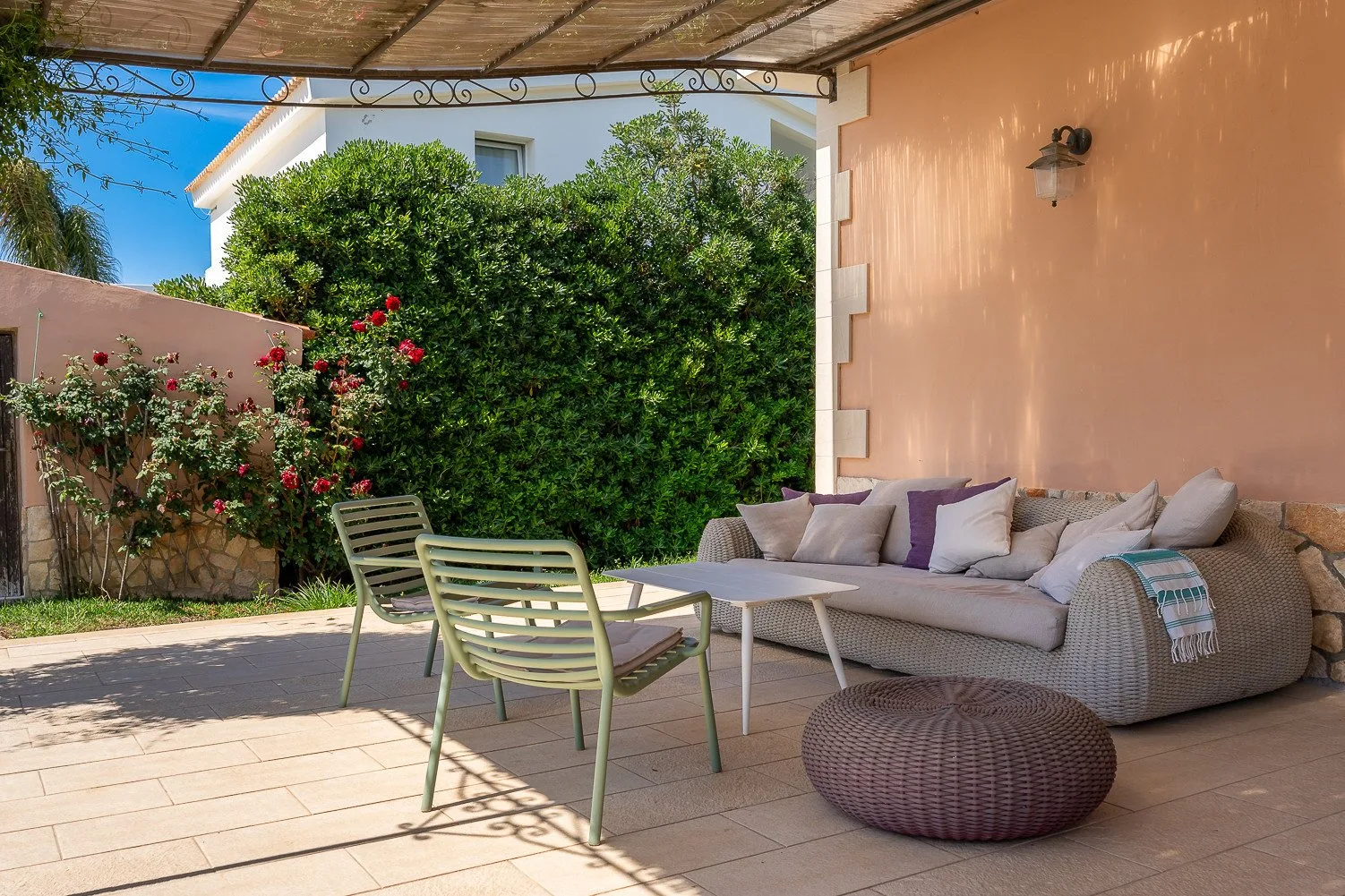 Una zona de estar exterior cubierta con un sofá con cojines y sillas de patio.
