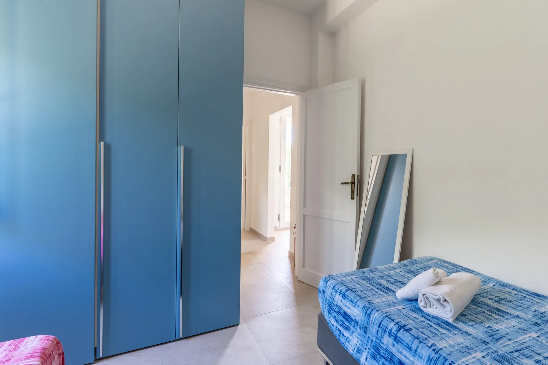 Un dormitorio con armarios azules, una cama y una puerta abierta.